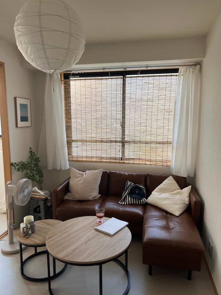 茶色のレザーソファとすだれが配置された清潔感のあるミニマルなリビングルーム