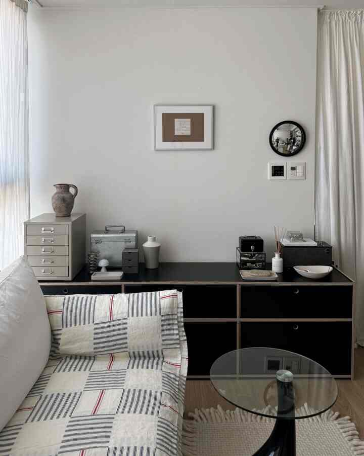 白と黒の調和が美しいリビング、ミニマルなソファと収納キャビネットが配置された雰囲気のあるインテリア