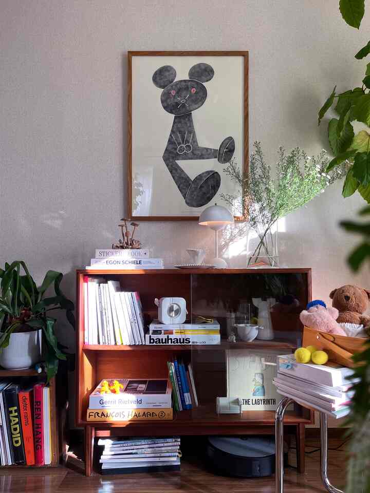 自然な木目調と緑の植物が調和したリビング、中央に配置された本棚が印象的な落ち着いた空間