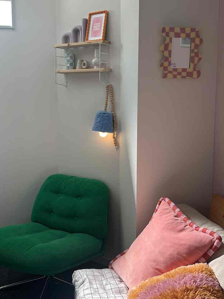 A cozy Korean interior space featuring a green armchair and pink cushions against pink and white walls
