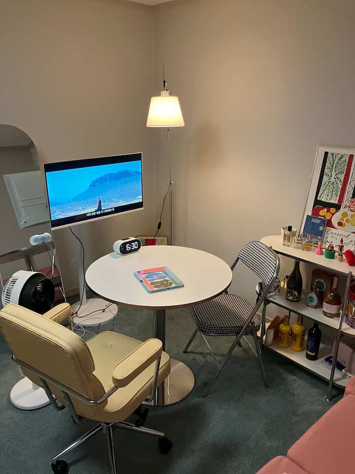 白とグレーの色調の小さな円形ダイニングルーム、モダンなオフィスチェアと照明が配置された雰囲気のある空間