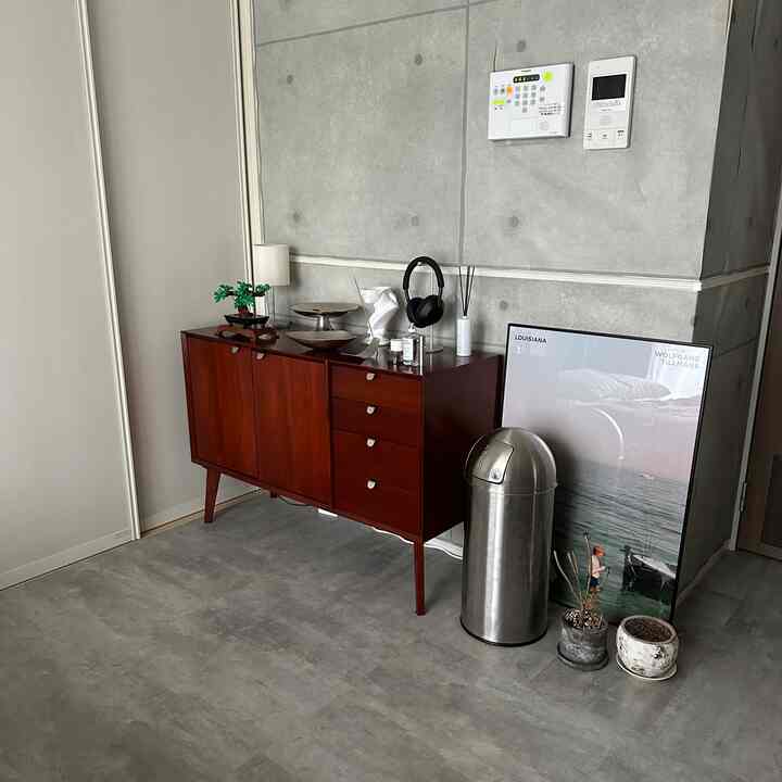 グレーのコンクリート壁と床、赤茶色のキャビネットが配置されたシンプルなインダストリアルスタイルの空間