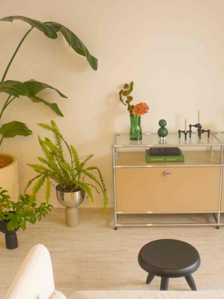 Beige and white toned living room featuring black stool and plants with a natural modern atmosphere