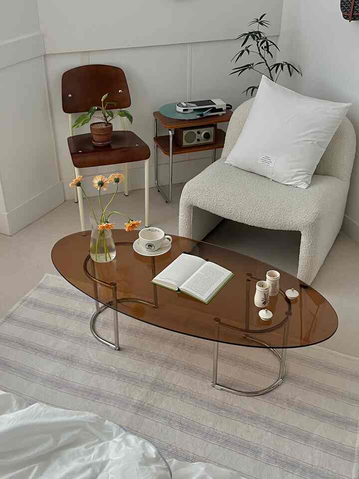 アイボリーとブラウンのトーンが特徴的なリビング、ミッドセンチュリーモダンスタイルのアームチェアとブラウンのガラステーブルが配置された落ち着いた空間