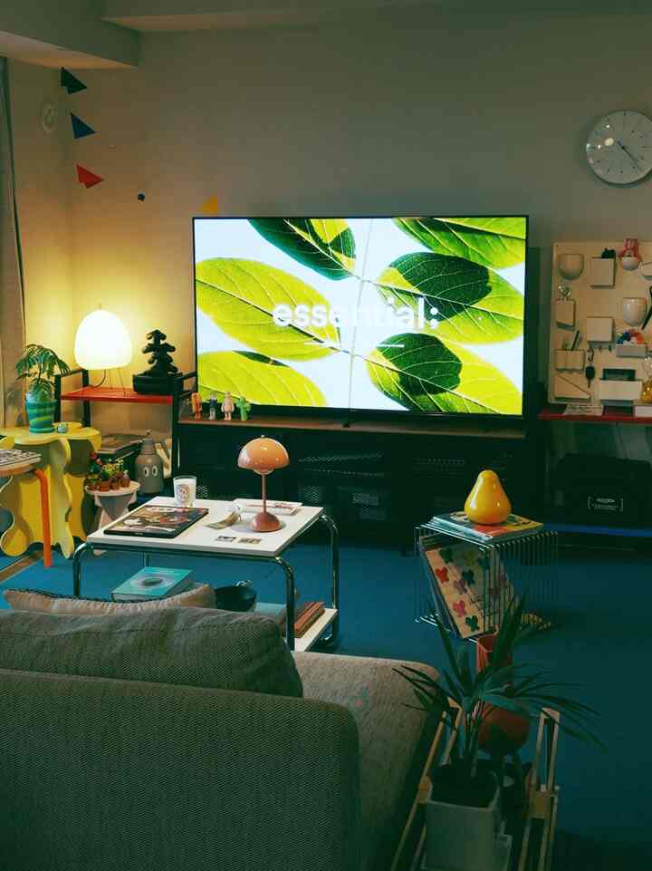 Blue carpeted living room featuring yellow side tables and sofa with natural and retro vibes