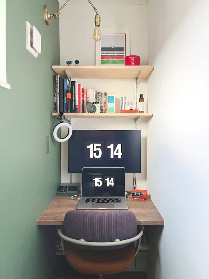 Natural toned small study featuring desk, computer, and organized wall shelves with books