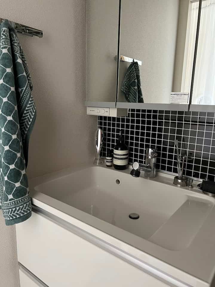 白と黒のタイル背景が調和したモダンな洗面台空間、シンプルで清潔感のあるインテリア