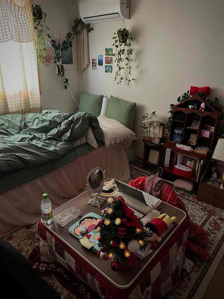 Natural toned studio apartment bedroom featuring kotatsu table and plants with a cozy atmosphere