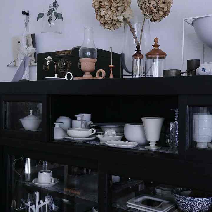 A navy-toned cabinet centrally placed, neatly arranged with white bowls and transparent glassware, showcasing a minimalist interior