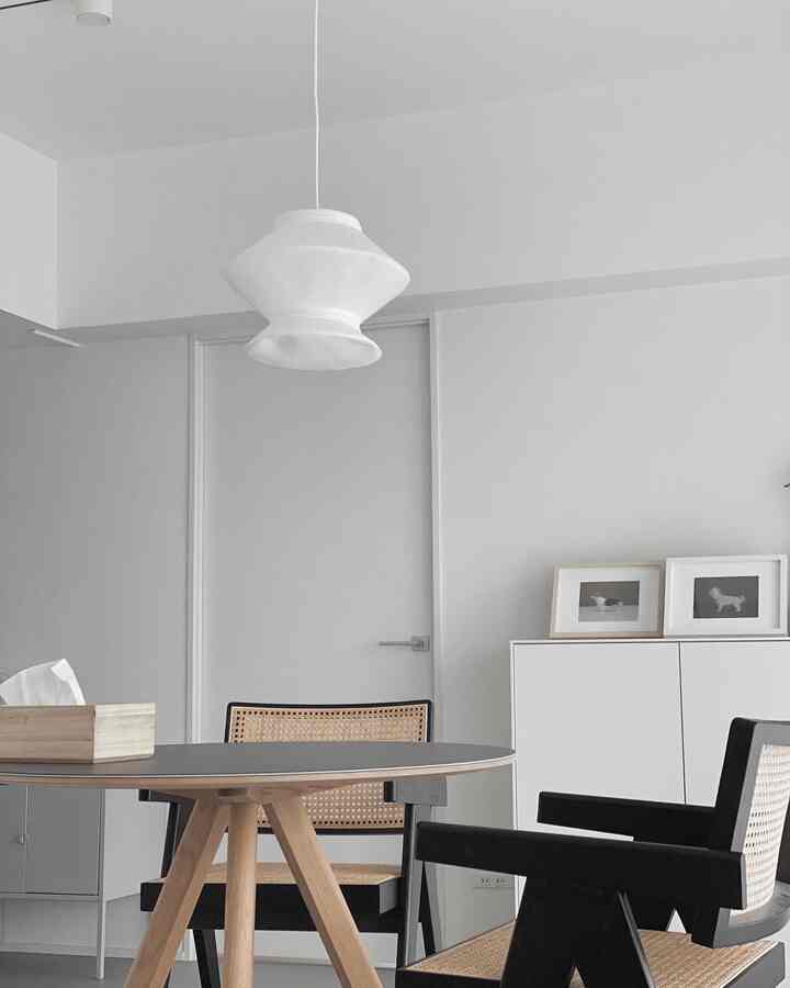 白とナチュラルトーンのモダンダイニング、丸テーブルとラタンチェアが配置されたシンプルで清潔感のある空間