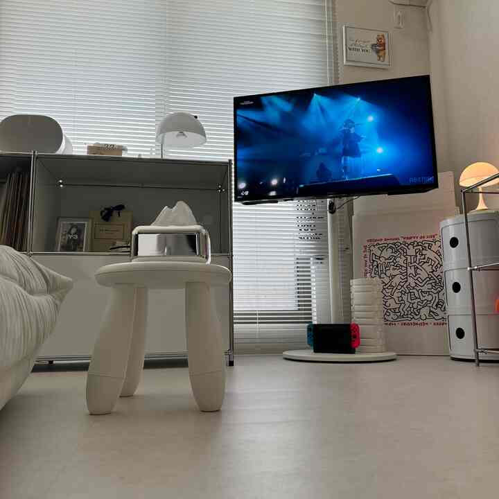 Bright white toned living room featuring a central white stool and sofa in a clean minimalist setting