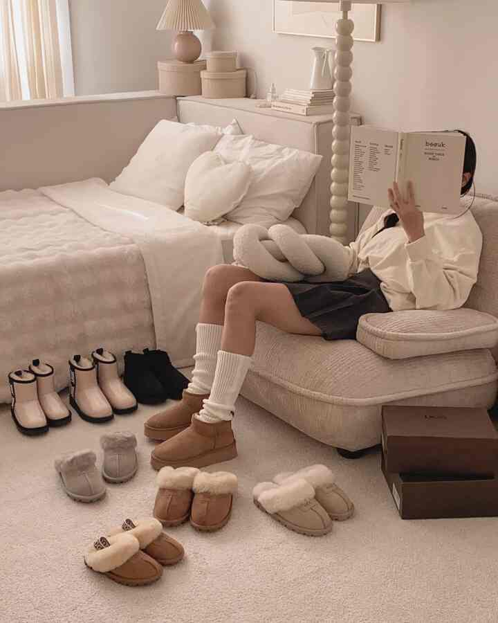 ベージュとホワイトの色調の寝室兼リビングスペース、ベージュのソファとベッド、複数のUGGブーツが配置された落ち着いた自然な雰囲気のインテリア