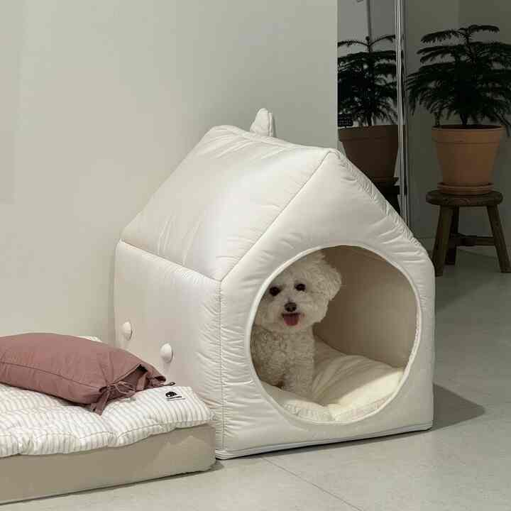 明るい白とナチュラルな色調の空間に、白いペットハウスとふたつの犬用ベッドが配置されたペットフレンドリーなインテリア