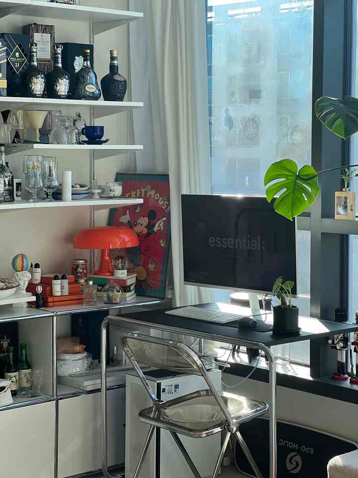 白と黒のトーンのモダンなホームオフィス、窓辺に植物が置かれた明るい作業空間