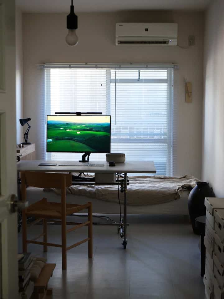 白と茶色のトーンが特徴の狭いワンルーム、机とベッドが効率的に配置されたナチュラルモダンのホームオフィス環境