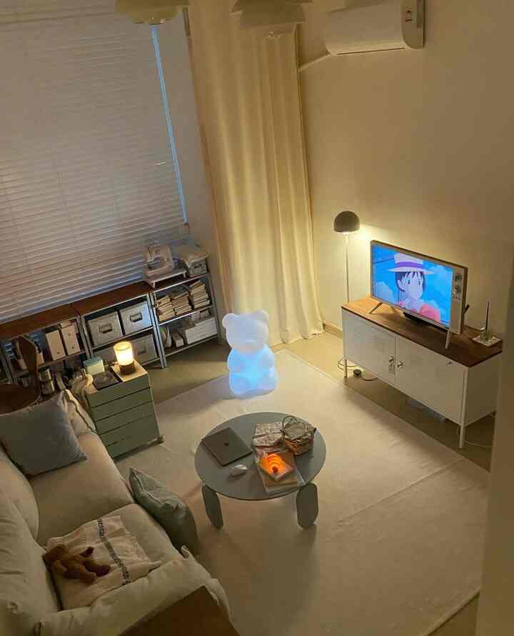 ベージュと木目調のワンルームリビング、ソファとラグ、ムードライトが配置された雰囲気のあるインテリア