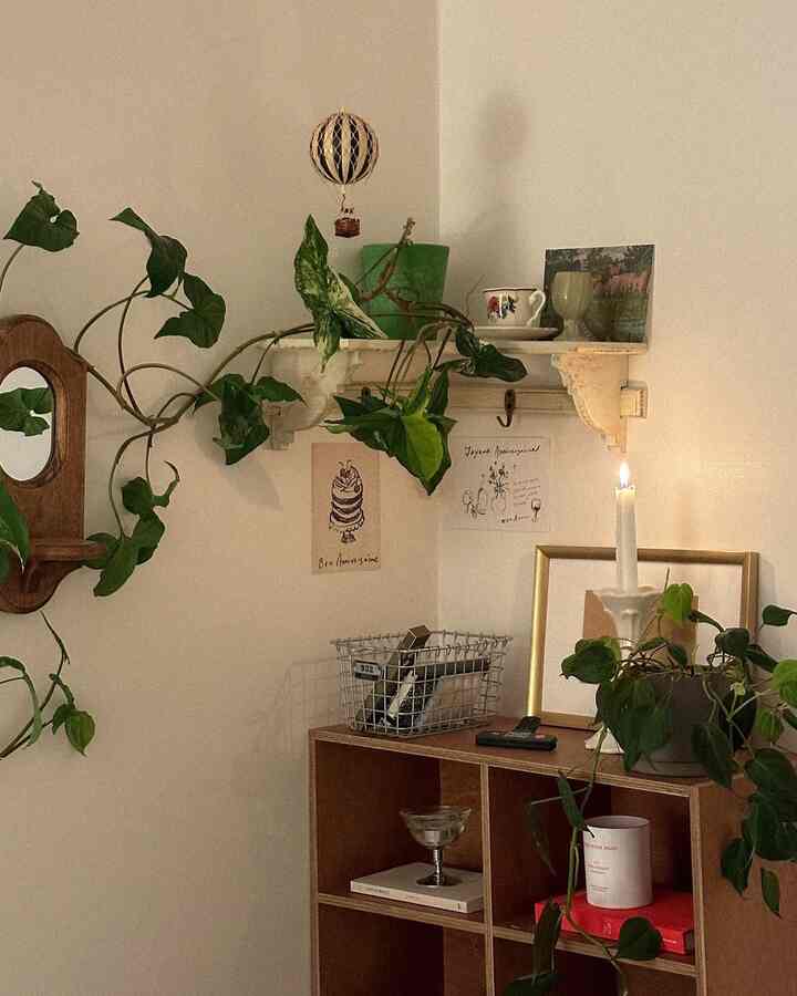 Natural-toned corner space with wall shelf, bookshelf, and candle holder creating a cozy vintage atmosphere