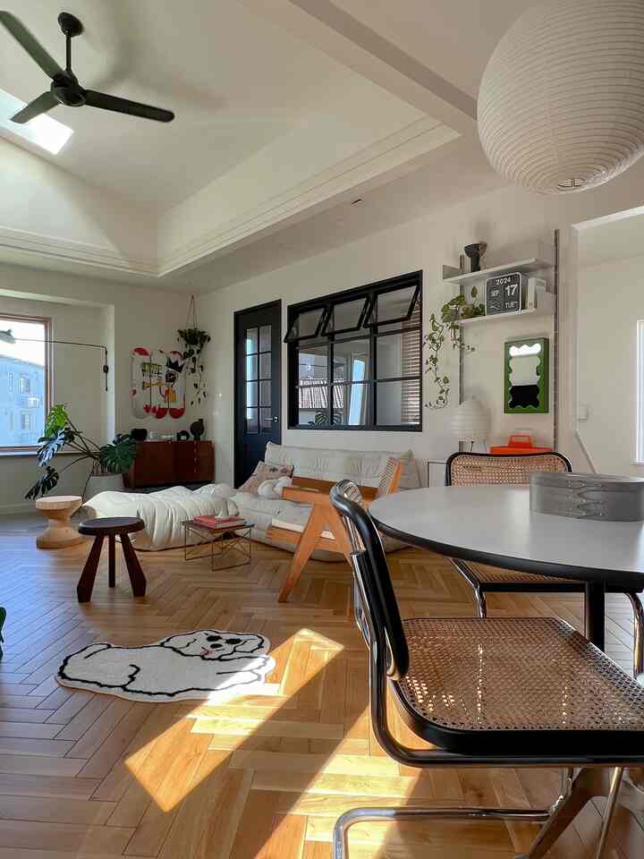 明るくナチュラルなリビング、白いソファとミッドセンチュリーモダン家具、ペットマットとペンダントライトが配置された印象的な空間