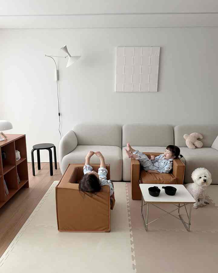 Beige and brown toned living room featuring kids' sofas with children and a white dog, creating a warm and natural atmosphere