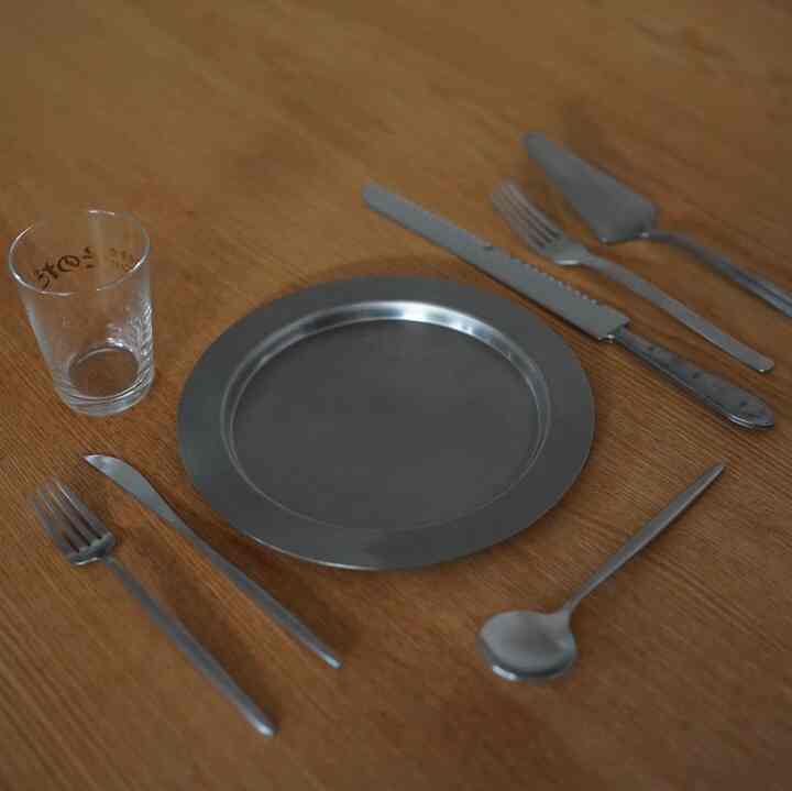 シルバーのカトラリーとグラスが置かれた木製テーブルの上のシンプルなキッチン用品