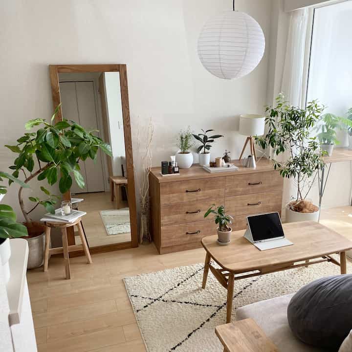 ナチュラルな木目調と植物が調和するリビング、木製家具と紙製ペンダントライトが配置された印象的な空間