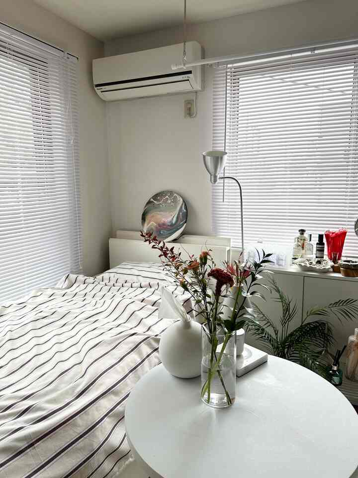 Modern bedroom in white and silver tones featuring a floor lamp and plants in a compact space