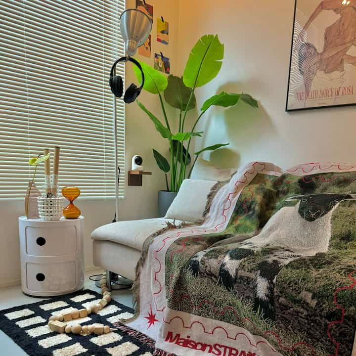 White and green toned living room featuring a sofa and large plants, creating a cozy, natural atmosphere