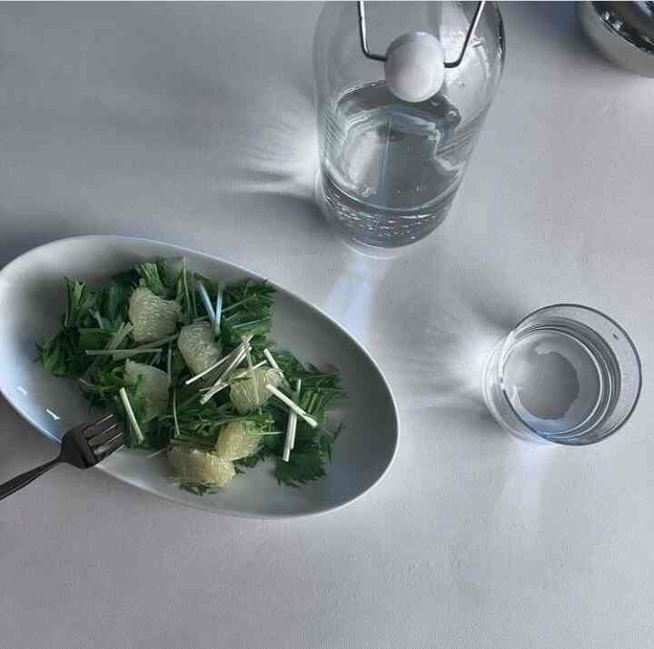 白を基調としたダイニングテーブルにオーバルプレートとガラスのボトル、コップが置かれたシンプルな朝食のインテリア