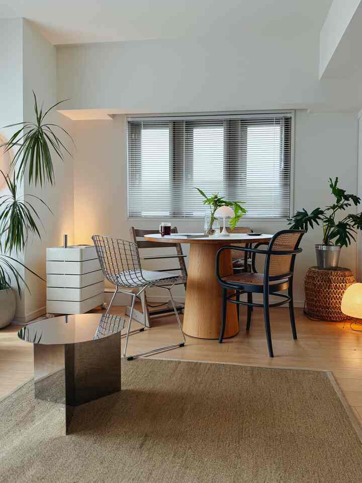 Natural color beige-toned dining room featuring a round wooden dining table, various dining chairs, and a natural fiber rug creating a cozy atmosphere