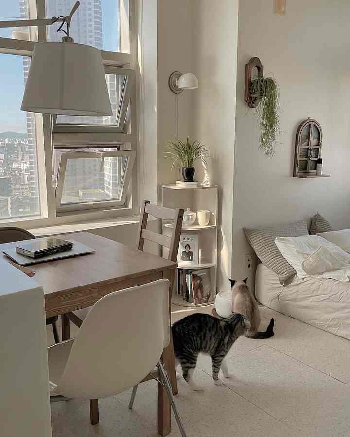 White and wood tone living room featuring dining table and chairs, sofa, and two cats in a cozy setting