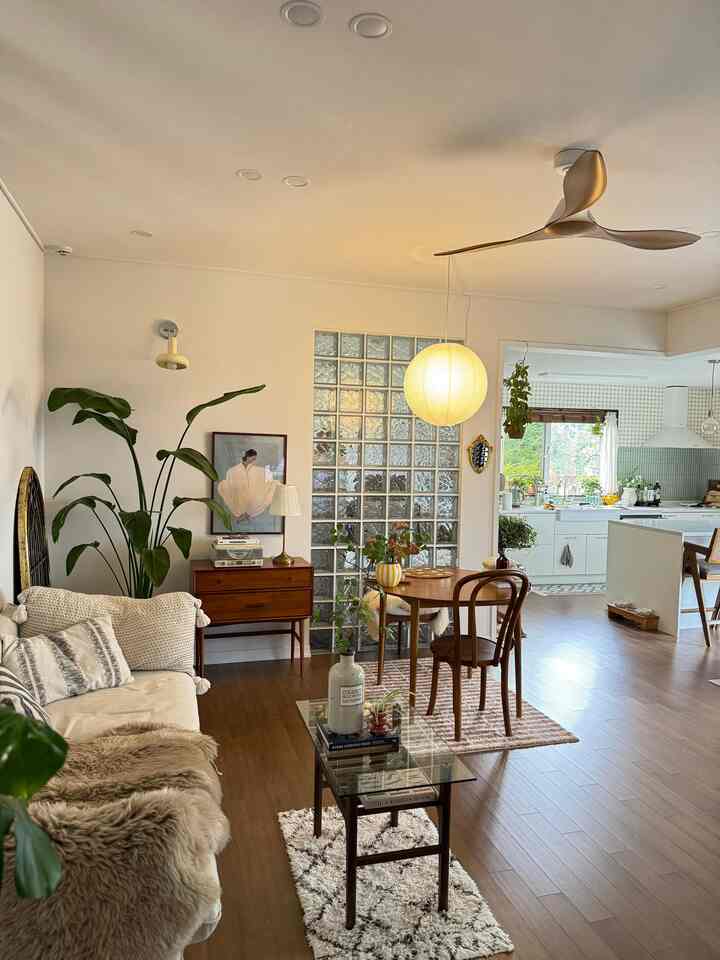 Warm wood tones and natural modern style living room featuring dining table, sofa, lighting, and plants in a cozy space
