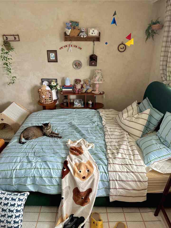 Beige and wood-toned bedroom featuring a green fabric bed with a cat resting on it, complemented by cozy decorative elements