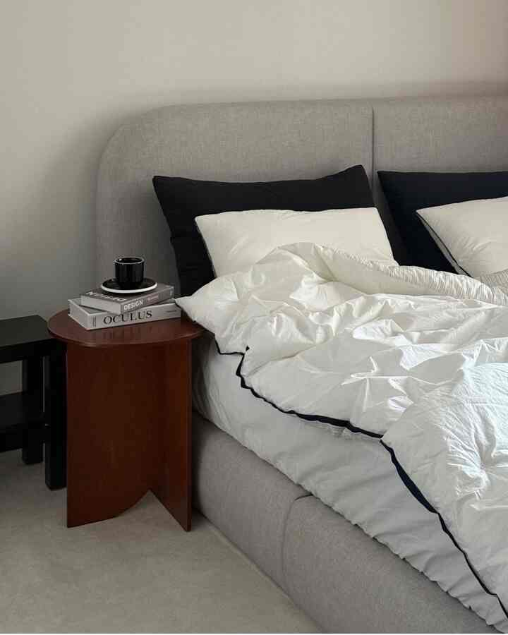 Gray and white toned bedroom featuring a modern bed and wooden nightstand in a clean setting