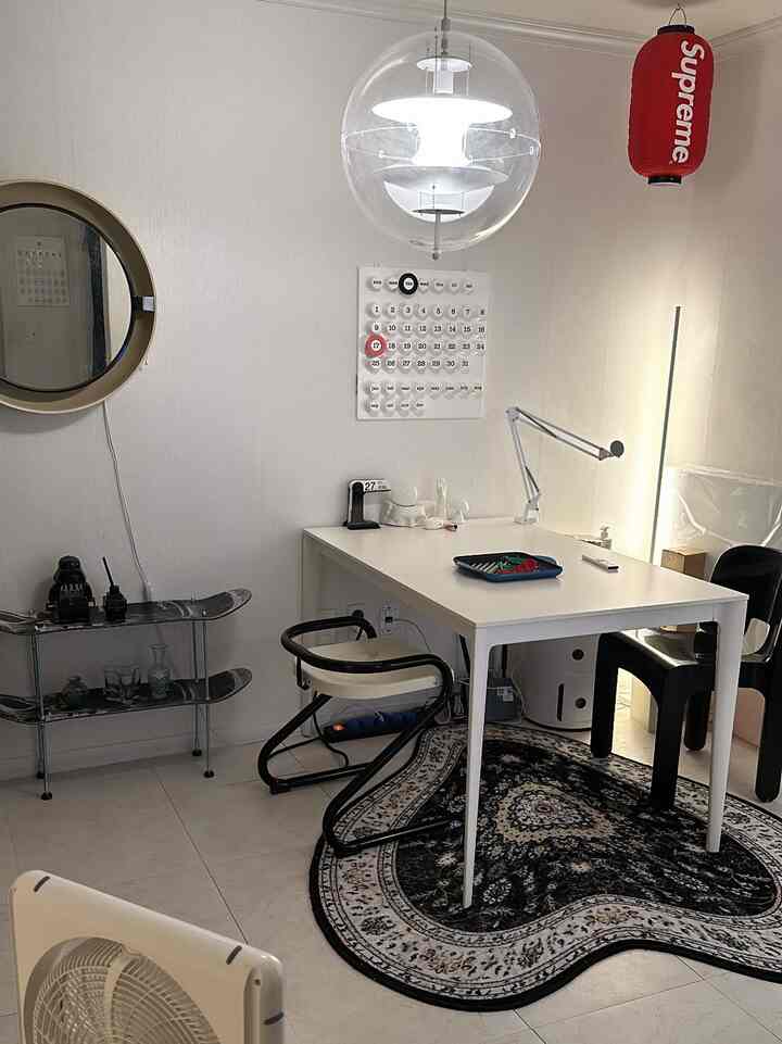 A white and black toned living room combined with a home office, featuring a simple white desk and black chairs in a minimal style interior
