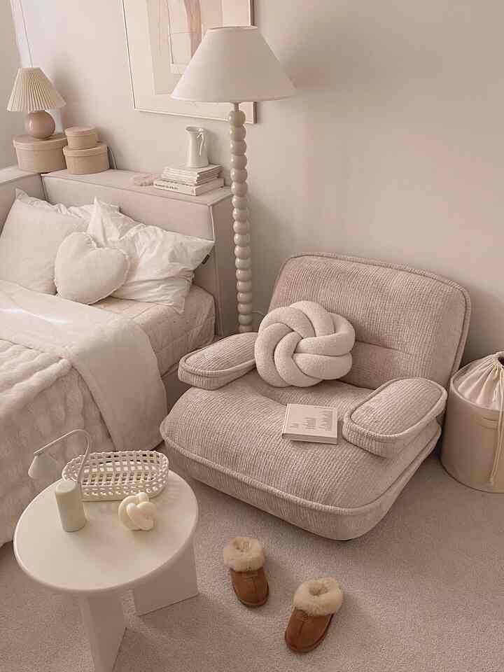 温かみのあるベージュとアイボリーのトーンでまとめられた居心地の良い寝室、低い座椅子ソファと柔らかな照明が配置されたシンプルで快適なインテリア