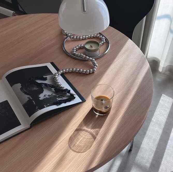 木目調のラウンドダイニングテーブルと白いランプが配置されたシンプルで落ち着いた雰囲気のインテリア