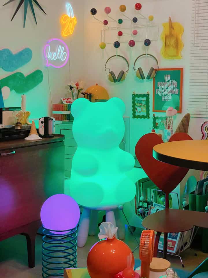 緑色に輝くクマ型ムードランプとカラフルなネオンライトが配置されたレトロな子供部屋のインテリア