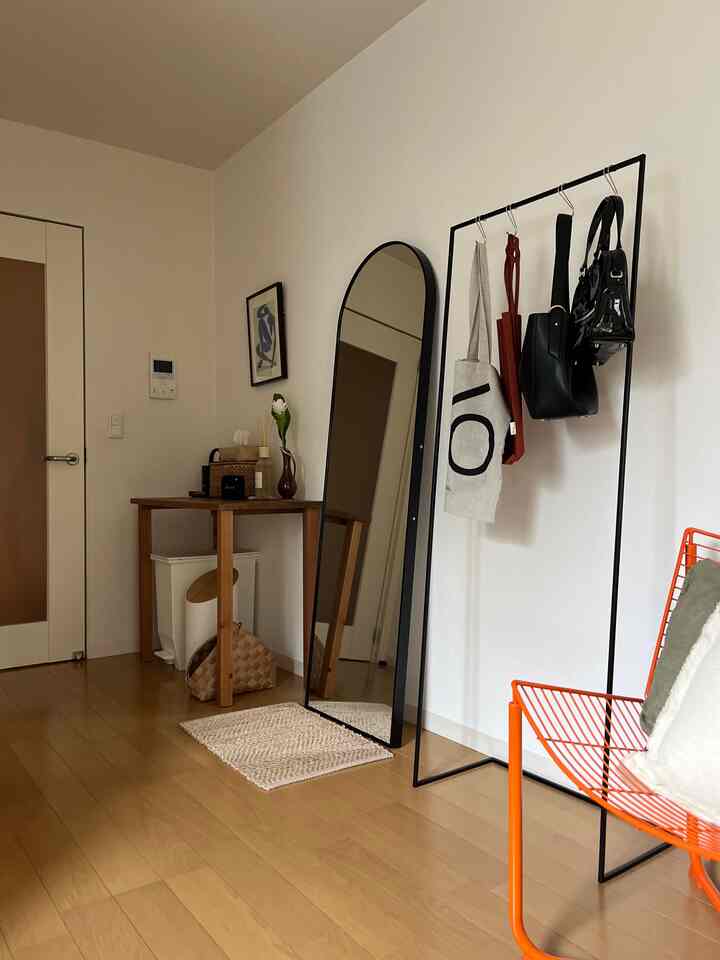 白い壁と茶色の床、黒い鉄製のクローゼットがあるすっきりした玄関スペース