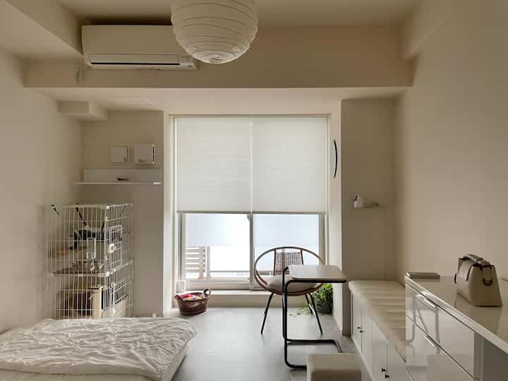 アイボリーとベージュの寝室、ホワイトの収納キャビネットとキャットケージが配置された清潔感のある自然な雰囲気のインテリア