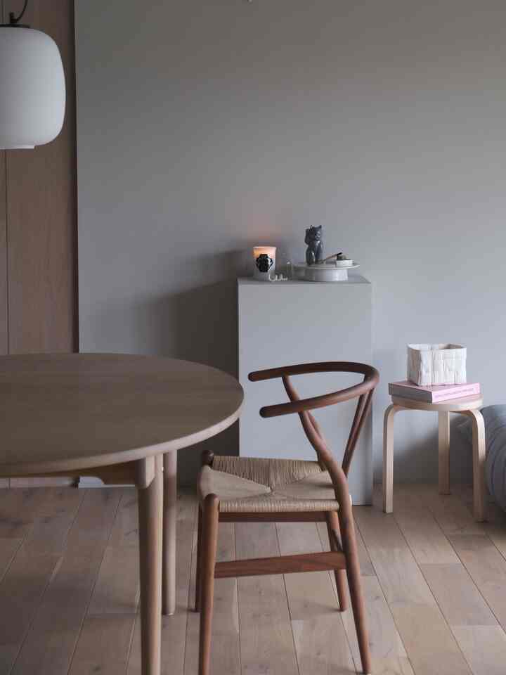 木目調とナチュラルカラーの調和が美しいダイニング、ラウンドテーブルとワイチェアが置かれた落ち着いたインテリア