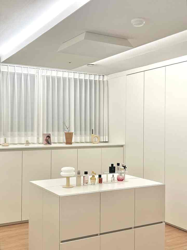 明るいホワイトトーンのウォークインクローゼット、ビルトインクローゼットと収納キャビネットが配置されたミニマルで整った空間