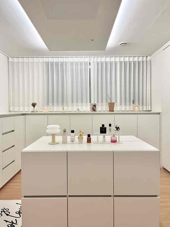 白とナチュラルカラーのミニマルなキッチンスペース、広い化粧台と洗練されたオブジェが配置された雰囲気のあるインテリア