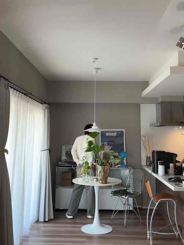 白とグレーの色調のダイニングルーム、中央に白い円形のカフェテーブルと椅子を配置したナチュラルモダンなインテリア