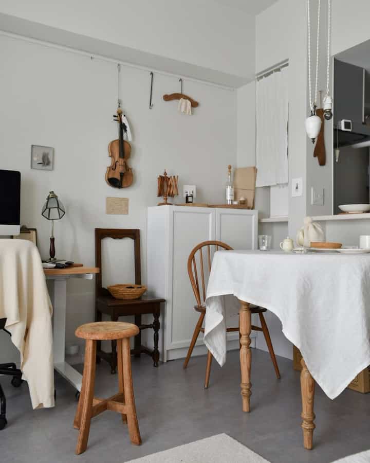 白い壁とナチュラルブラウンの木製家具が配置された、狭い一人暮らしの1LDKダイニングとホームオフィスの空間