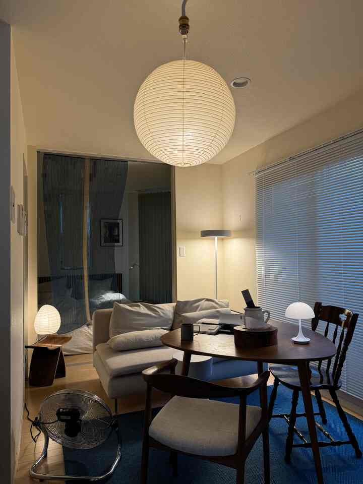 柔らかなホワイトとブルーのトーンのコンパクトなリビングダイニング、ナチュラルモダンなペンダントライトが配置された印象的な空間