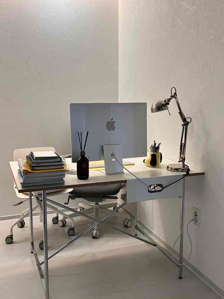 白とシルバーのトーンのホームオフィス空間、整然と配置されたデスクとコンピュータがあるモダンな作業環境