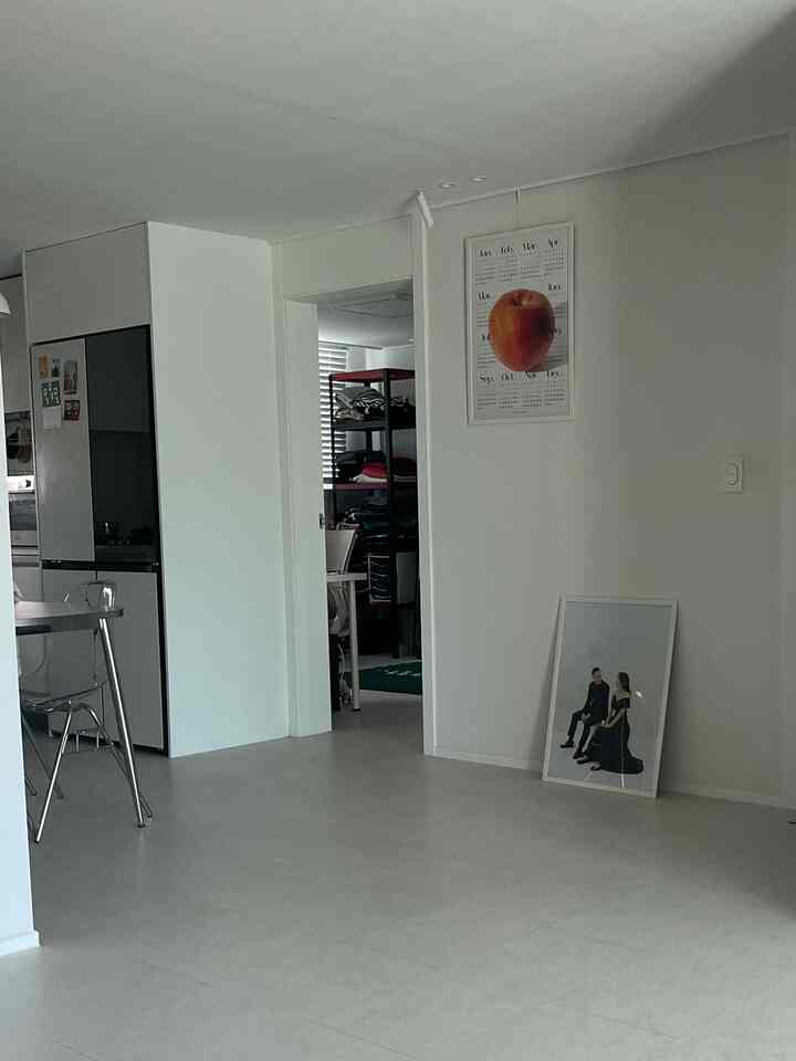 白を基調としたキッチンと玄関の空間、シンプルな額縁とすっきりとした壁面が配置されたモダンなインテリア