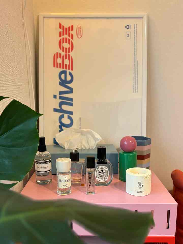 Natural-toned objet space featuring various perfumes and candles displayed on a pink storage unit