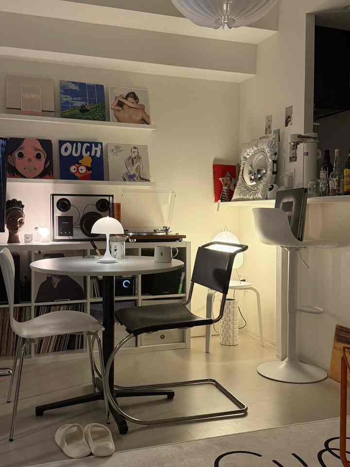 白とモノトーンのリビング、丸テーブルとテーブルランプ、バースツールが配置された雰囲気のあるインテリア