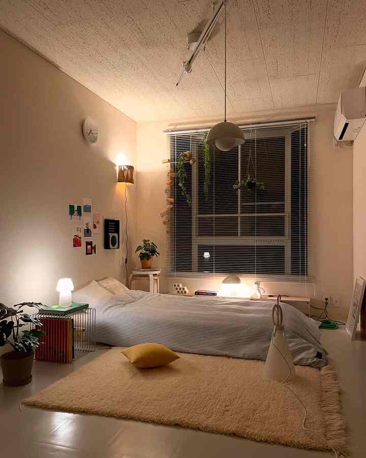 温かみのあるベージュと白の色調の寝室、ストライプ柄の掛け布団カバーとナチュラルなインテリアが配された雰囲気のある空間